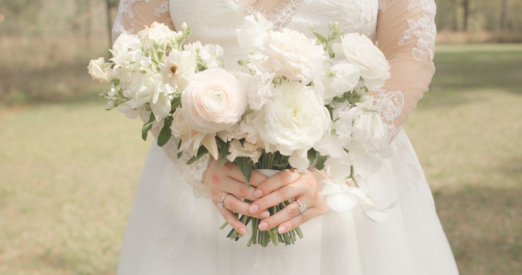 During the pre-ceremony section of our wedding videography timeline, a bride holds her bouquet in front of her with both hands. Each hand features a diamond ring.
