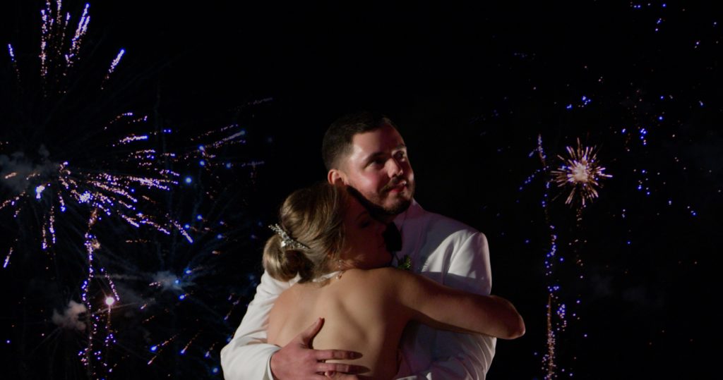 Groom holds bride in his arms during their firework exit. Bride shared how to plan a wedding yourself after a successful evening!